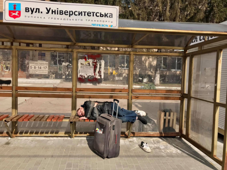 Чоловік спить на зупинці громадського транспорту в Черкасах.